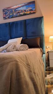 - un lit avec une tête de lit bleue et des serviettes dans l'établissement Nel Cuore Di Napoli, à Naples