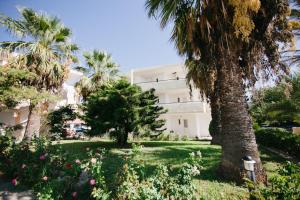 a large white building with palm trees and flowers at Artemis Comfort&Pleasure in Faliraki