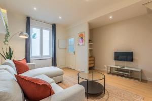 a living room with a couch and a tv at Maison 2 chambres calme, proche tram in Mouvaux