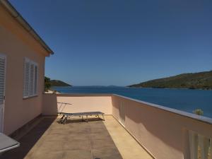 un banco en un balcón con vistas al agua en Holiday House Soline, en Veli Rat