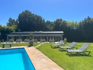 a group of chairs and a swimming pool in a yard at Constantia Winelands Lodge in Constantia