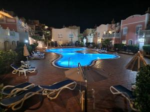 ein Pool mit Stühlen und Sonnenschirmen in der Nacht in der Unterkunft Sunset Rooftop Terrace apartment in Palm-mar