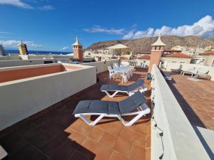einen Balkon mit Liegestühlen und Tischen auf dem Dach in der Unterkunft Sunset Rooftop Terrace apartment in Palm-mar