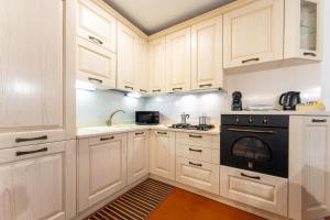 a kitchen with white cabinets and a black oven at Fuori da ZTL - Asiago a due passi da tutto in Asiago +45 photos