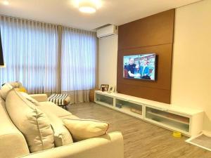 a living room with a couch and a flat screen tv at RCM Vilas - Porto Picarras in Piçarras