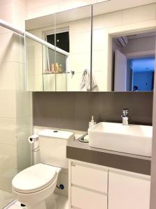 a bathroom with a white toilet and a sink at RCM Vilas - Porto Picarras in Piçarras