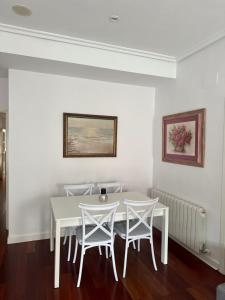 Un comedor blanco con una mesa y sillas blancas. en La Terraza, en Ávila