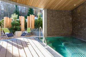 a swimming pool with chairs and a brick wall at The Alpina Mountain Resort in Tschiertschen