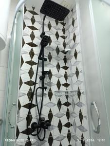 Una ducha con azulejos blancos y negros en una pared. en Garfield Family Apartman 2, en Soko Banja