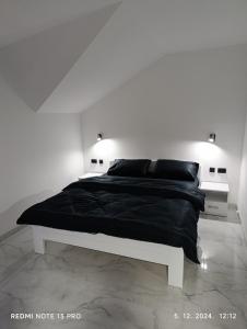 Un dormitorio blanco con una cama negra con dos luces. en Garfield Family Apartman 2, en Soko Banja