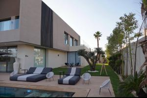 a house with two couches and chairs next to a pool at Marrakech Oasis Retreat - 5-Bedroom Villa with Private Pool in El Makina