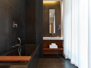 a bathroom with a tub and a sink and a mirror at Le Metropolitan, Paris Tour Eiffel, a Tribute Portfolio Hotel in Paris