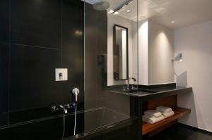 a bathroom with a shower with a sink and a mirror at Le Metropolitan, Paris Tour Eiffel, a Tribute Portfolio Hotel in Paris