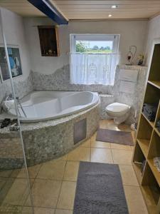 a bathroom with a large tub and a toilet at Haus Wallapampa im Grünen entspannen in Landscheide