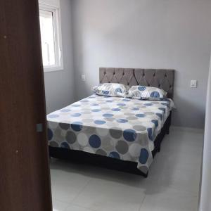 ein Schlafzimmer mit einem Bett mit einer blau-weißen Bettdecke in der Unterkunft Casa no Rio Mampituba in Torres