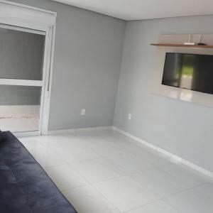 ein weißer Raum mit einem Fernseher an der Wand in der Unterkunft Casa no Rio Mampituba in Torres + 13 Fotos