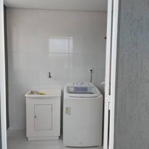 eine kleine weiße Küche mit Waschmaschine und Trockner in der Unterkunft Casa no Rio Mampituba in Torres