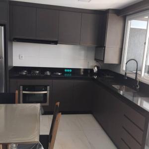 eine Küche mit schwarzen Schränken, einem Waschbecken und einem Tisch in der Unterkunft Casa no Rio Mampituba in Torres