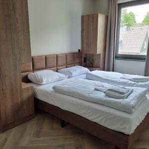 ein Schlafzimmer mit zwei Betten mit weißen Laken und einem Fenster in der Unterkunft Wellnessappartement Winterberg D4 in Winterberg