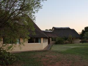 a house with a thatched roof and a yard at Ngata Safari Lodge in Hammanskraal