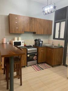 a kitchen with wooden cabinets and a stove and a table at Cozy home at pearl marina garuga entebbe in Wakiso