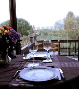 a table with a plate and two wine glasses at Isleham River Lodge in Isleham