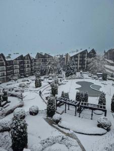 un parc enneigé avec un banc et un étang dans l'établissement Aspen Golf and Ski Resort, à Bansko