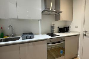 ハウンズローにあるLuxury Studio Flat Hounslow Centralのキッチン(白いキャビネット、シンク、コンロ付)