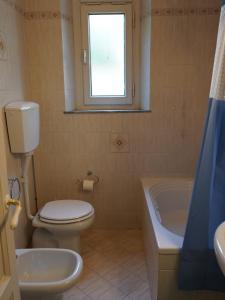 a bathroom with a toilet and a tub and a window at Casa Natalina in Montecatini Terme +30 photos