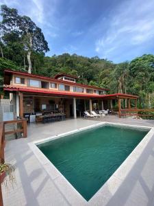 a house with a swimming pool in front of it at Paraíso em Juquehy in Bertioga