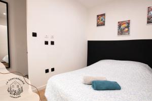 a bedroom with a bed with a blue pillow on it at Les Eugènes, appartements in Lens