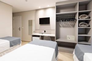 a bedroom with two beds and a desk and a tv at Hotel Pitol in Balneário Camboriú