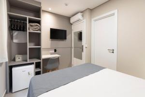 a bedroom with a bed and a desk and a television at Hotel Pitol in Balneário Camboriú