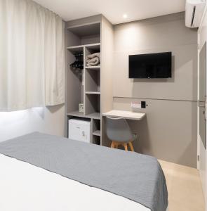 a bedroom with a bed and a desk and a tv at Hotel Pitol in Balneário Camboriú