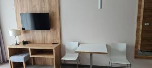 ein Zimmer mit einem Schreibtisch und einem Fernseher an der Wand in der Unterkunft Aparthotel Apartamenty Czarna Góra 131 in Heudorf