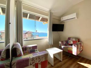 a living room with two chairs and a large window at Pousada Areia Cristal in Bombinhas