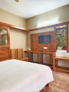 a bedroom with a bed and a flat screen tv at JUNGLE VALLEY AYURVEDIC SPa RESORT in Meppādi +105 photos