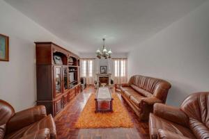 a living room with leather furniture and a chandelier at Pérola Achadense Guesthouse in Achada