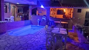 a swimming pool in a house with a table and chairs at Pousada casa nostra in Piúma