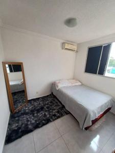 a small bedroom with a bed and a mirror at Aconchego Apartamento in Várzea Grande