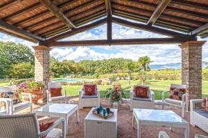 eine Terrasse mit weißen Stühlen und Tischen sowie einer Holzdecke in der Unterkunft Dimora di Castroncello in Castiglion Fiorentino