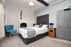 a bedroom with a bed and a blue chair at The Halford Bridge Inn in Shipston-on-Stour +6 photos
