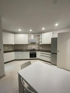 una cucina con mobili bianchi, tavolo e sedie di Turris Apartments, SKYLINE historic center Bologna a Bologna