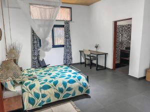 Un dormitorio con una cama y una mesa y una ventana. en Villa Masay Antananarivo, en Antananarivo