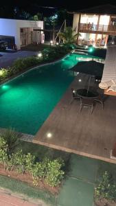 a swimming pool with a table and an umbrella at Paraíso da Lagoa, Praia de Itacimirim Village novo! in Itacimirim