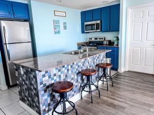 a kitchen with blue cabinets and a counter with stools at Sterling Reef 1603 Waterfront in Panama City Beach