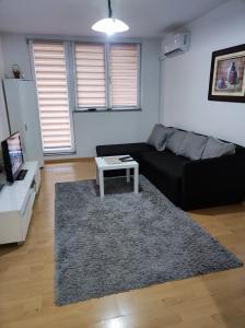 un salon avec un canapé noir et une table dans l'établissement Amna apartman, à Sarajevo