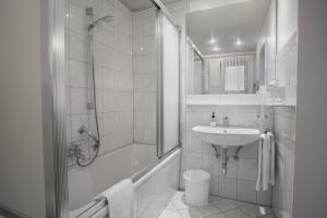 a white bathroom with a shower and a sink at Trail Hotel Oberstaufen in Oberstaufen +17 photos