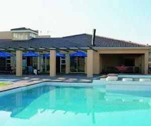 una piscina frente a un edificio con sombrillas azules en Unit 75 Hermanus Beach Club, en Hermanus