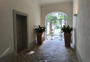 an empty hallway with two potted plants and an open door at Maison Rebecca - Superior Suite Apartment in Ravenna